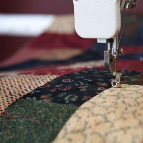 Prešívaná deka s blokovým vzorom v zemitých farbách.